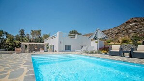 Uma área de piscina moderna com piscina azul límpida, edifício branco e área de estar externa.