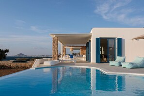Ein moderner Poolbereich mit freiem Blick auf das Meer und einem Berg in der Ferne.