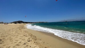 A beach with clear blue water, sandy shore, and distant mountains. - Villa Salt Mikri Vigla Naxos (Mikri Vigla)
