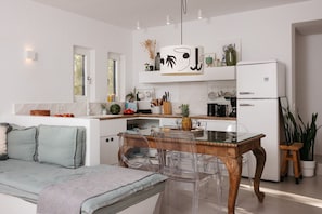 Una cocina moderna con armarios blancos, una mesa de comedor de madera y sillas transparentes.