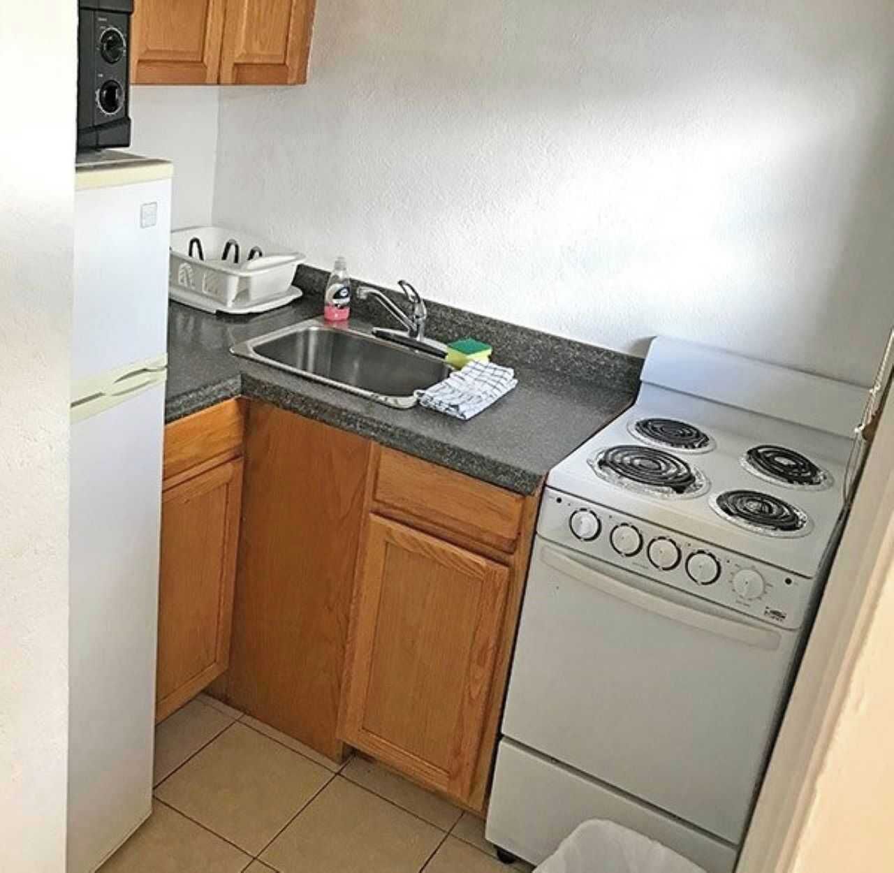 A compact kitchen with a stove, sink, and wooden cabinets.