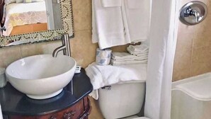 A bathroom with a wooden vanity, a white sink, a toilet, and a bathtub. - Two double bed studio with full kitchen on 2nd floor . (Pompano Beach)