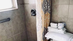 Een badkamer met een douche, toilet en een handdoekrek.
