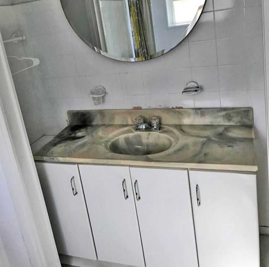 A bathroom with a sink, mirror, and white cabinets.
