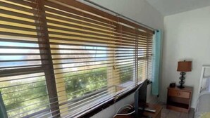 A bedroom with a wooden desk, a bed, a nightstand, and a window with blinds. - King Studio with Sofa Sleeper, Full Kitchen,Ocean Views (Pompano Beach)
