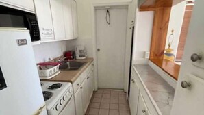 A narrow kitchen with white cabinets, a stove, a microwave, and a coffee maker. - King Studio with Sofa Sleeper, Full Kitchen,Ocean Views (Pompano Beach)