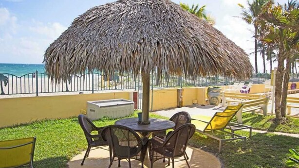 An outdoor seating area with a thatched umbrella, a round table, and chairs. - King Studio with Sofa Sleeper, Full Kitchen,Ocean Views (Pompano Beach)