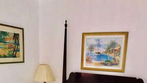 A room with a bed, a lamp, and two framed pictures on the wall. - Queen Studio-Full Kitchen,Tiki Area, Overlooking the Beach (Pompano Beach)