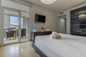 Hotelkamer met een bed, een televisie, een bureau met stoel, en een balkon met een barbecue.