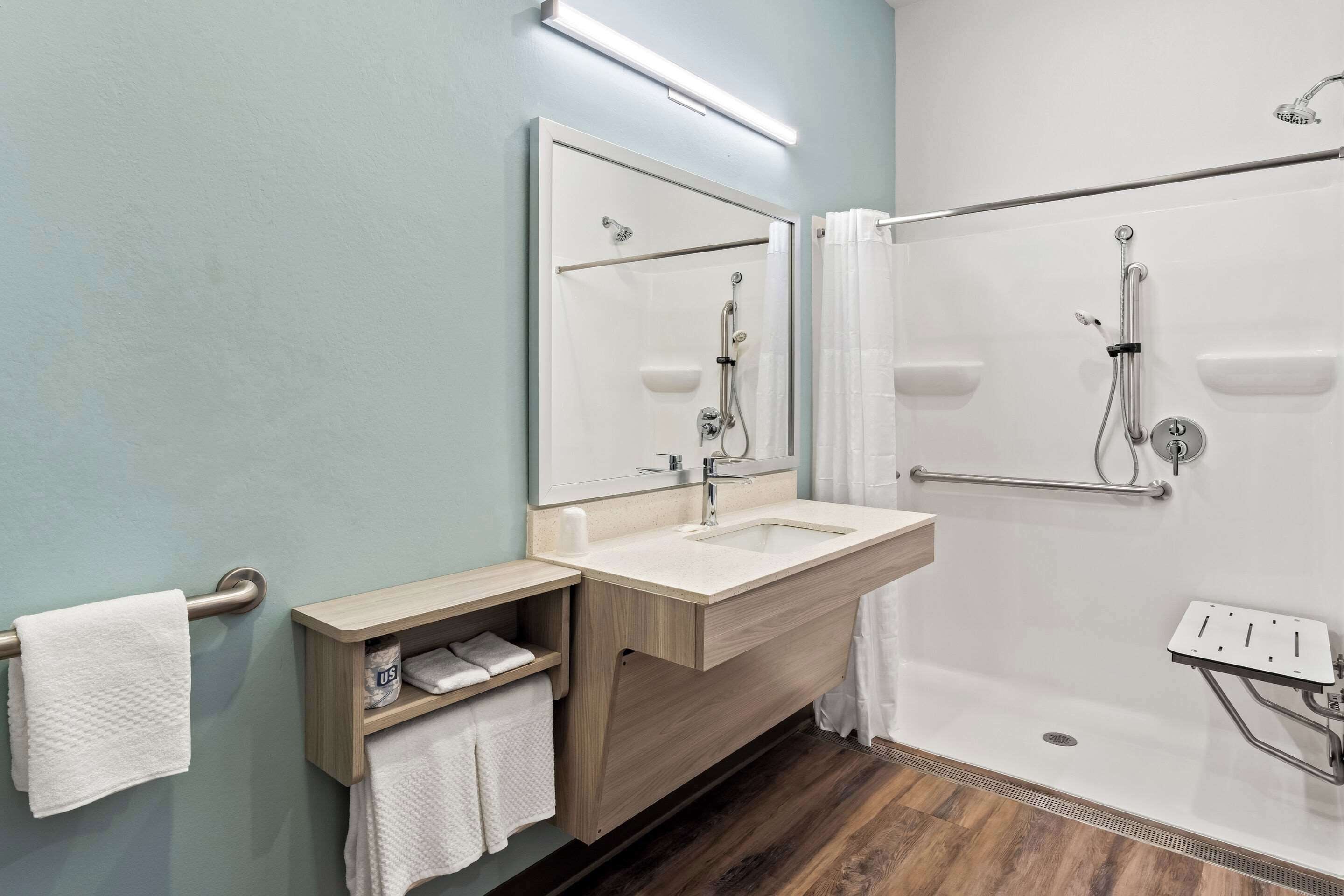 A modern bathroom with a sink, mirror, and shower.