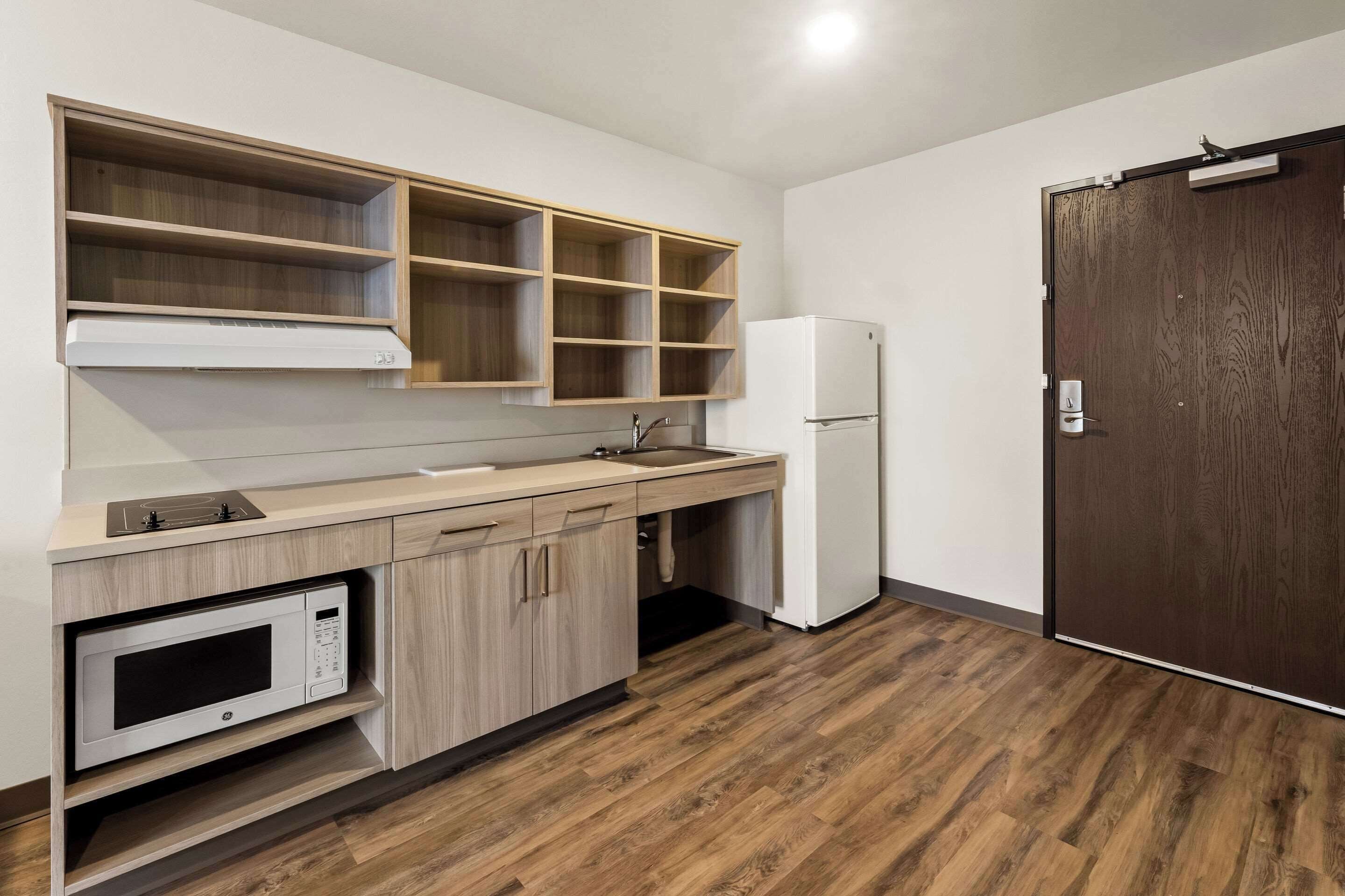 A compact kitchen with a microwave, sink, and wooden cabinets.