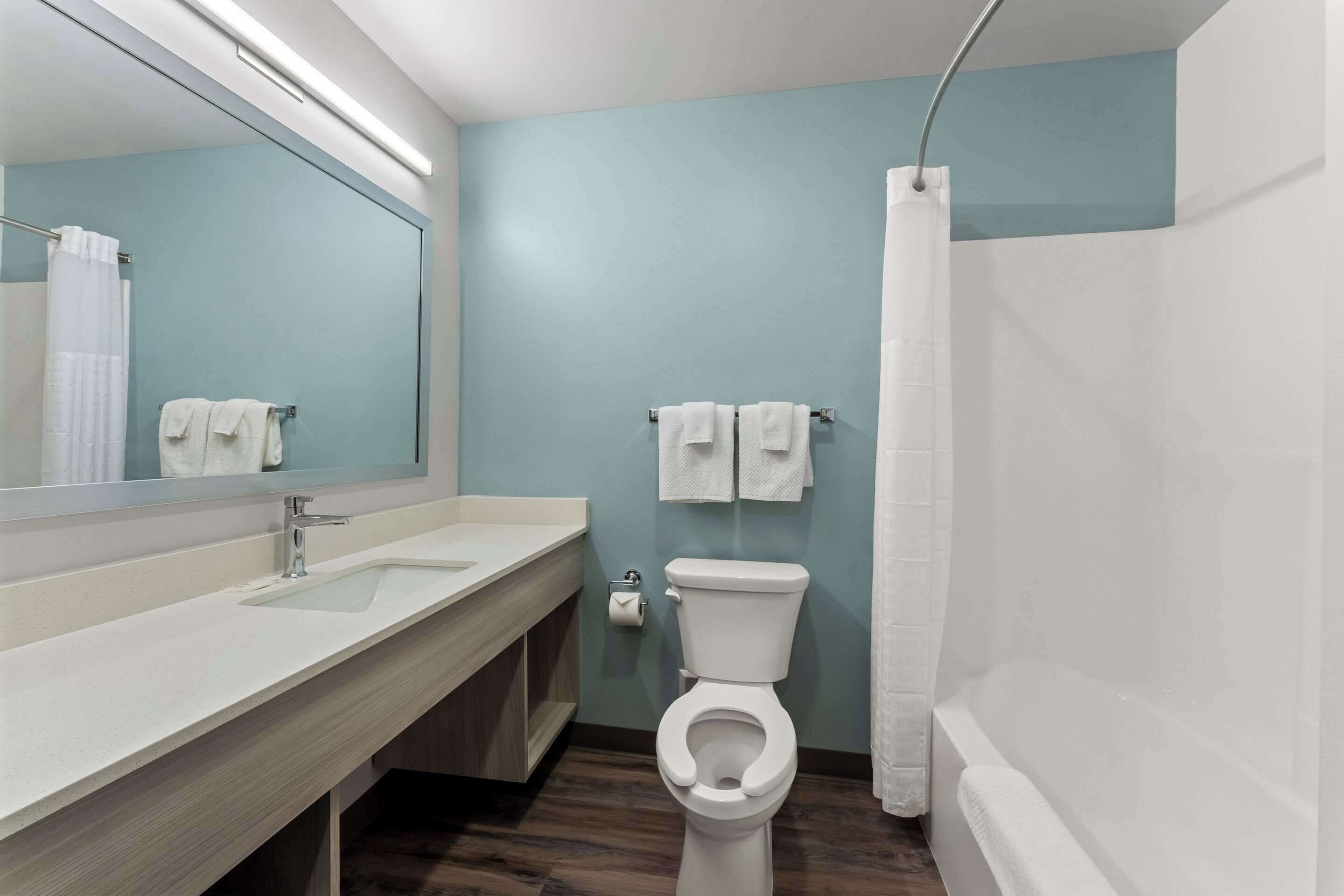Un baño moderno con un lavabo blanco, un inodoro y una cortina de ducha.