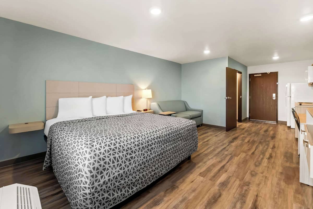 Une chambre d’hôtel comprenant un lit, une table de chevet, un canapé, un bureau et une kitchenette.
