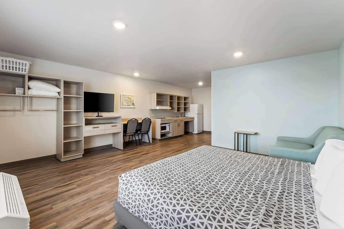 Une chambre d’hôtel moderne dotée d’un grand lit, d’un bureau, d’une télévision et d’étagères intégrées.