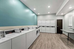 Un moderno cuarto de lavandería con varias lavadoras, secadoras y armarios de almacenamiento.