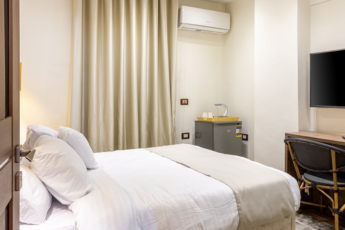 Une chambre d’hôtel équipée d’un lit, d’un bureau, d’une chaise, d’un climatiseur et d’un téléviseur.