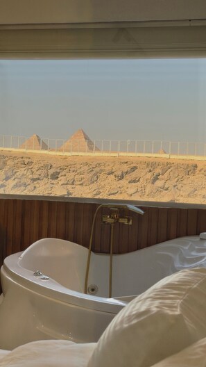 A bathtub with a view of pyramids in the background. - Shiny Pyramids Boutique Hotel (Giza)