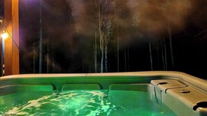 Ein Whirlpool mit Blick auf einen Wald bei Nacht.