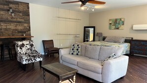 A living room with a sofa, armchair, coffee table, and a ceiling fan.