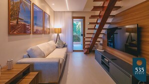 A modern living room with a sofa, a TV, and framed pictures on the wall.