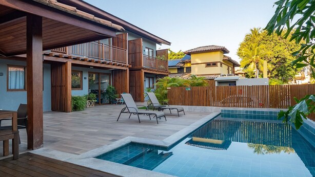 A pool area with a wooden deck, lounge chairs, and a small pool.