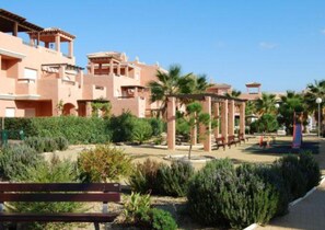 Guests can relax in the resort's central courtyard surrounded by lush greenery and stucco buildings.