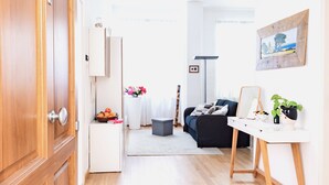 A modern living room with a wooden door, white cabinets, a grey ottoman, a black sofa, a white coffee table, and a framed picture on the wall. - "AL PALAZZO" - Pergola Suite - 500m from the Duomo (firenze)