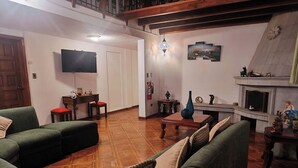 A living room with a fireplace, a television, and a dining area. - Hotel Sweet Garden (Cumbayá)