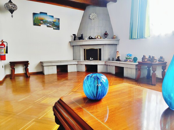 A room with a fireplace, a wooden table, and a blue globe. - Hotel Sweet Garden (Cumbayá)