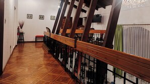 A wooden staircase with a railing, a chandelier, and a fire extinguisher on the wall. - Hotel Sweet Garden (Cumbayá)