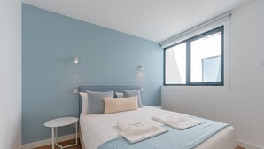 A bedroom with a bed, a small table, and a window.