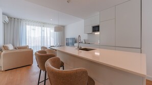 A modern kitchen with a central island, a built-in microwave, and a large window with sheer curtains.