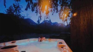 A hot tub in a natural setting with a mountainous backdrop.