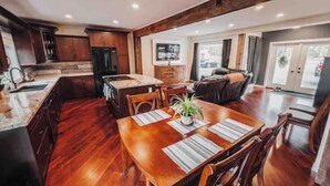 A spacious kitchen with wooden cabinets, a dining area with a large wooden table, and a cozy living room with a fireplace.