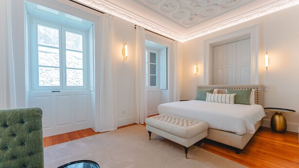 Ein Schlafzimmer mit einem großen Bett, einem grünen Sessel und einem kleinen Tisch.