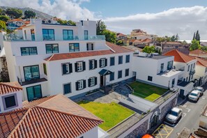 Un immeuble moderne à plusieurs étages, doté d’une cour intérieure, de balcons et d’un espace de stationnement.