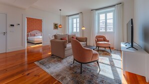 A modern living room with a sofa, armchairs, a coffee table, and a TV on a stand.