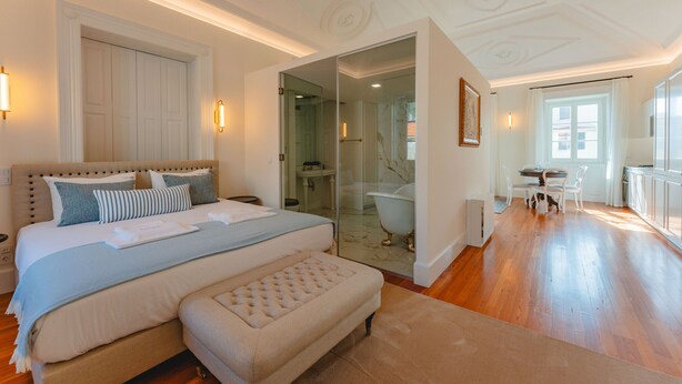 A spacious bedroom with a large bed, a sitting area, and a bathroom with a bathtub. - FLH Funchal A Quinta do Conde Suite II (Funchal)