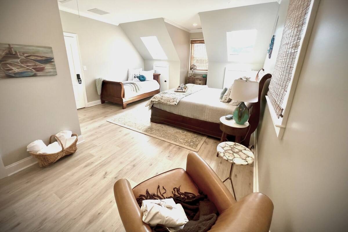 Un dormitorio moderno con una cama grande, una cama más pequeña, una silla y un escritorio.