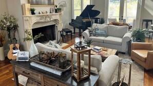 A living room with a fireplace, a grand piano, a couch, and a coffee table. - Lakeside Valley Vineyards B&B (Jasper)