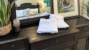A dark wooden dresser with a large mirror, a framed butterfly picture, and folded white towels. - Lakeside Valley Vineyards B&B (Jasper)