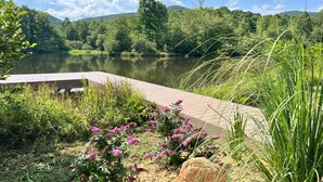 A serene lakeside view with a wooden dock, surrounded by lush greenery and flowering plants. - Lakeside Valley Vineyards B&B (Jasper)