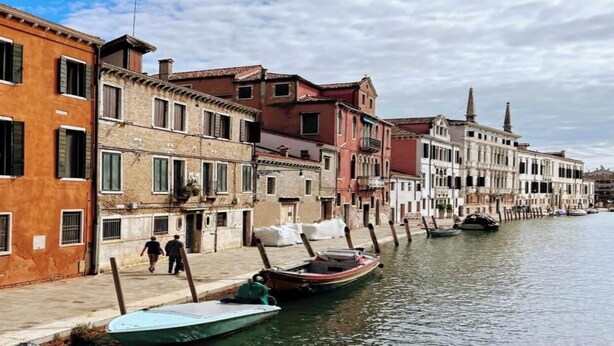 Un canal bordé de bâtiments d’un côté et où des bateaux sont amarrés le long de la rive.
