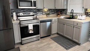 Una cocina moderna con electrodomésticos de acero inoxidable, armarios de gris claro y un salpicadero blanco y negro.