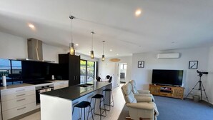 A modern kitchen with a central island, bar stools, a sofa, a TV, and a telescope.