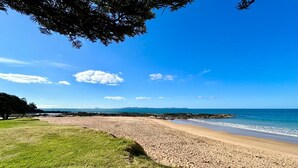 A beach with a grassy area and a rocky shoreline.