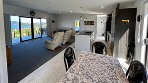 A modern living room with a large sliding glass door leading to a balcony with a scenic view.