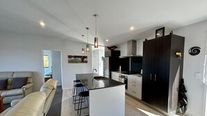 A modern kitchen with a central island, bar stools, and pendant lighting.