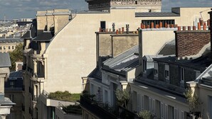 A historic building with classical architecture, including a prominent pediment and detailed carvings, situated above modern buildings with varied rooflines and balconies. - Top floor Paris studio - view of rooftops and monuments  (Paris)