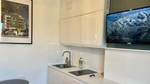 A compact kitchen with white cabinets, a sink, and a small round table. - Top floor Paris studio - view of rooftops and monuments  (Paris)
